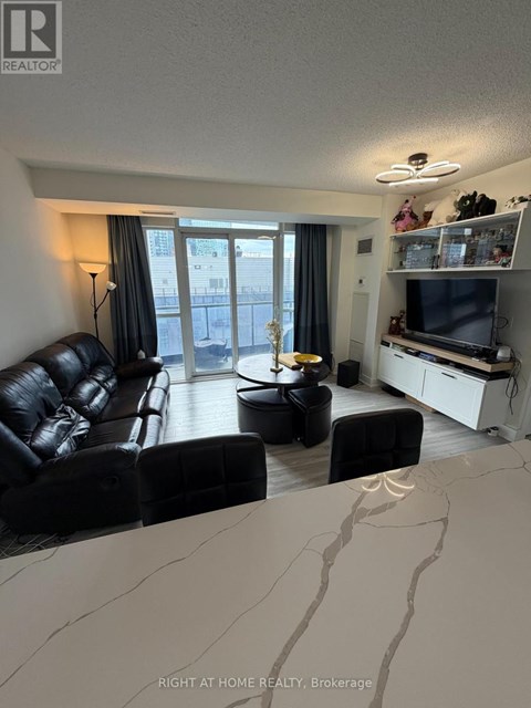 A living room with a black leather couch and a television.