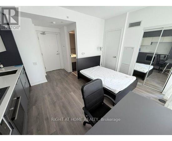 A bedroom with a bed, chair, and a desk.