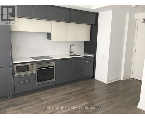 A modern kitchen with dark grey cabinets and stainless steel appliances.