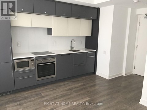 A modern kitchen with dark grey cabinets and stainless steel appliances.