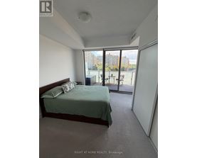 A bedroom with a bed, pillow, and a window overlooking a tennis court.
