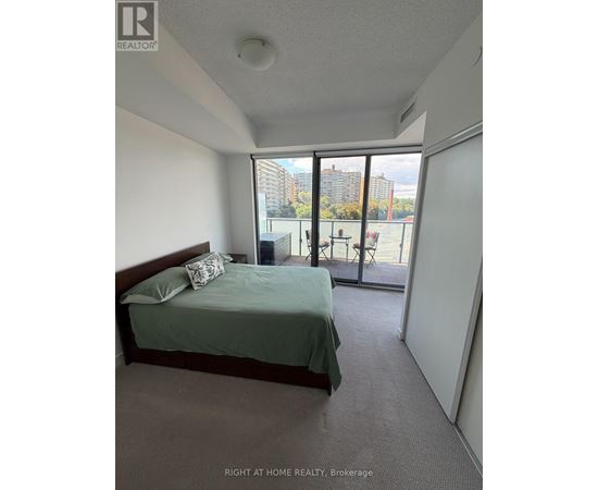 A bedroom with a bed, pillow, and a window overlooking a tennis court.