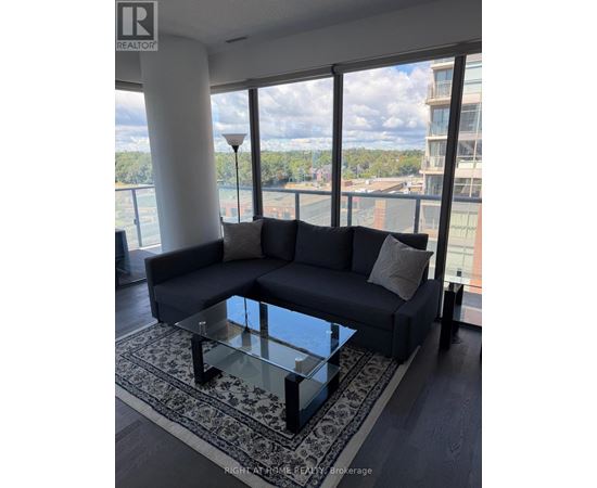 A living room with a large couch and a glass table.