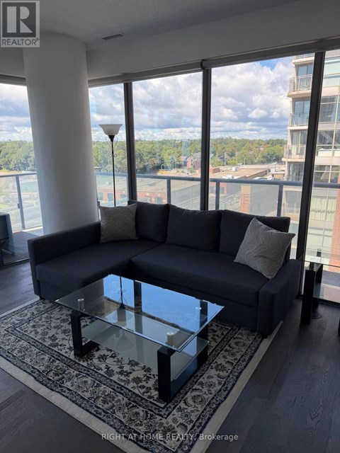 A living room with a large couch and a glass table.
