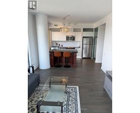 A modern kitchen with a bar stool and a glass table.