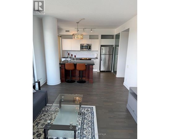 A modern kitchen with a bar stool and a glass table.