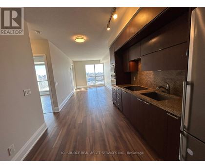 A kitchen with dark wood floors and a refrigerator on the right.