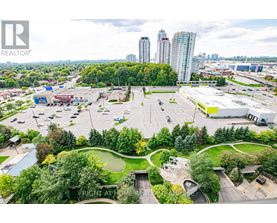 A parking lot with a green space in the middle and a building in the background.