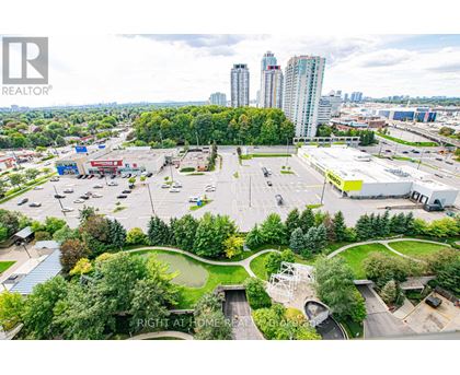 A parking lot with a green space in the middle and a building in the background.