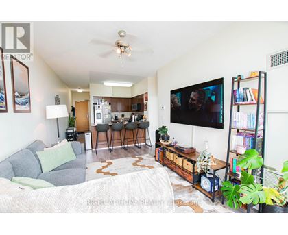 A living room with a grey couch and a television on the wall.
