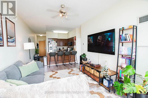 A living room with a grey couch and a television on the wall.