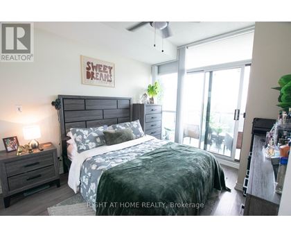 A bedroom with a bed, nightstand, and a ceiling fan.