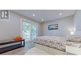 A bedroom with a bed, a bench, and a painting on the wall.