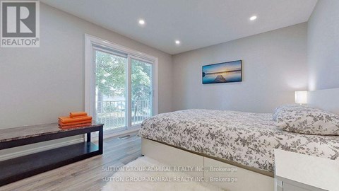 A bedroom with a bed, a bench, and a painting on the wall.