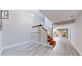 A spacious hallway with a staircase and a chandelier.