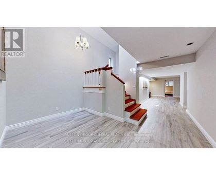 A spacious hallway with a staircase and a chandelier.