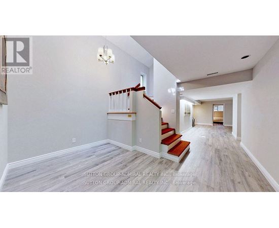 A spacious hallway with a staircase and a chandelier.