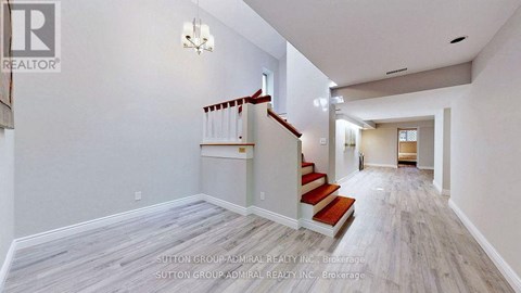 A spacious hallway with a staircase and a chandelier.