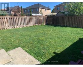 A backyard with a wooden fence and a green lawn.