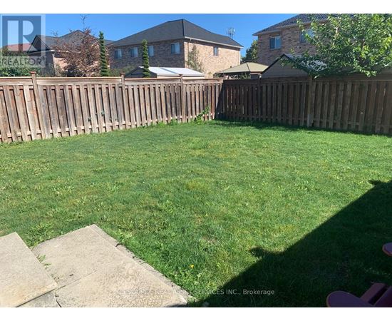 A backyard with a wooden fence and a green lawn.