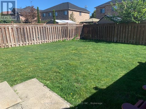 A backyard with a wooden fence and a green lawn.