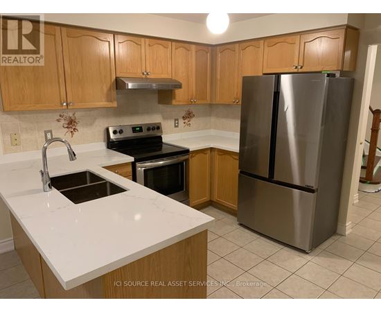 A kitchen with a stainless steel refrigerator, oven, and sink.