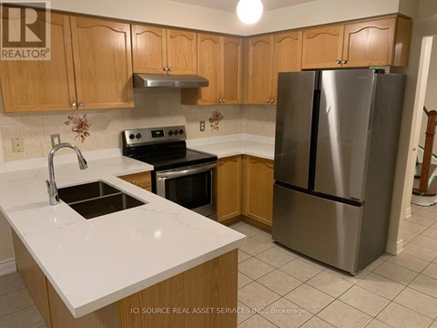 A kitchen with a stainless steel refrigerator, oven, and sink.
