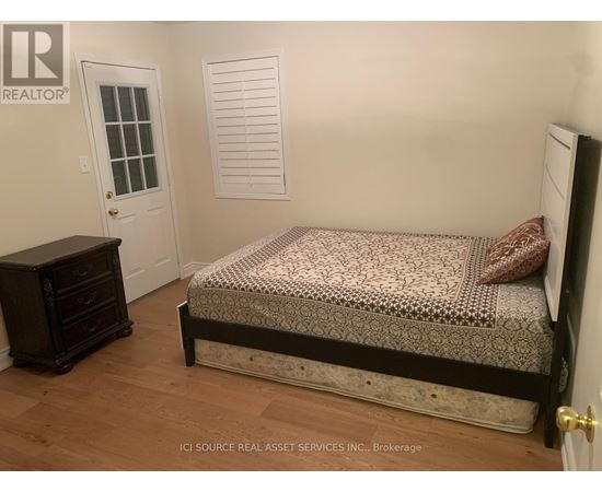 A bedroom with a bed, dresser, and window.