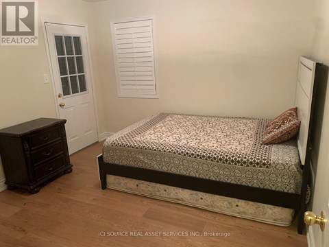 A bedroom with a bed, dresser, and window.