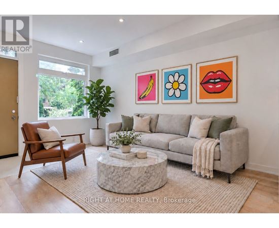 A living room with a grey couch, a brown chair, and a coffee table with a plant on it.