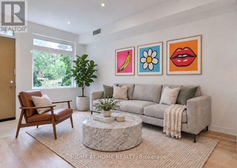 A living room with a grey couch, a brown chair, and a coffee table with a plant on it.