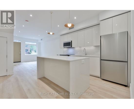 A modern kitchen with a refrigerator, microwave, and sink.