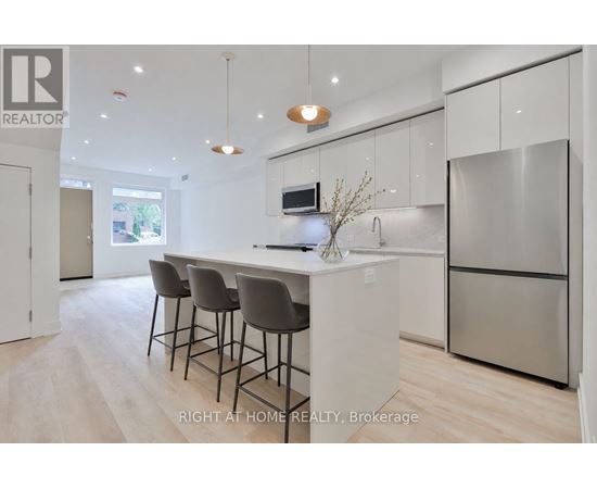 A modern kitchen with a bar area and a refrigerator.