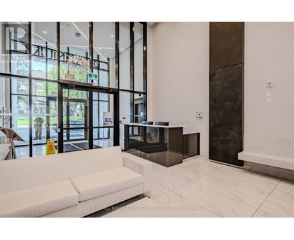 A real estate office with a white couch and a yellow spray bottle.