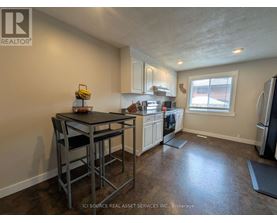 A kitchen with a table and chairs in the foreground and a refrigerator in the background.