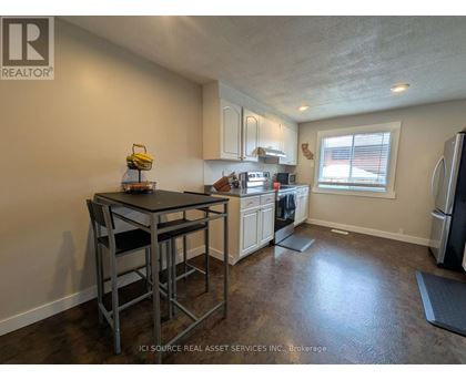 A kitchen with a table and chairs in the foreground and a refrigerator in the background.