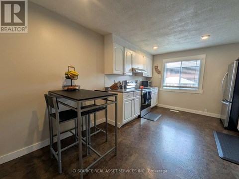A kitchen with a table and chairs in the foreground and a refrigerator in the background.