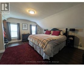 A bedroom with a bed, nightstand, and window.