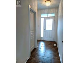 A hallway with a brown tile floor and white walls.