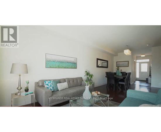 A living room with a grey couch and a painting on the wall.