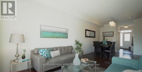 A living room with a grey couch and a painting on the wall.