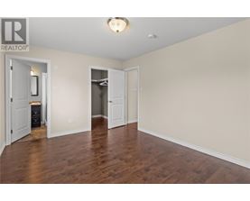 A spacious room with wood flooring and white walls.