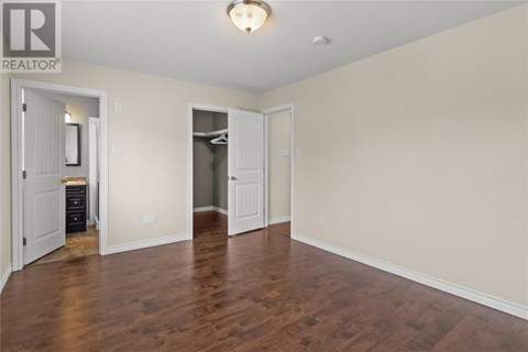 A spacious room with wood flooring and white walls.