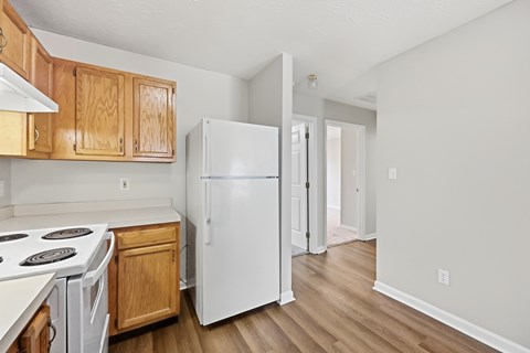 A kitchen with a white refrigerator and wooden cabinets.