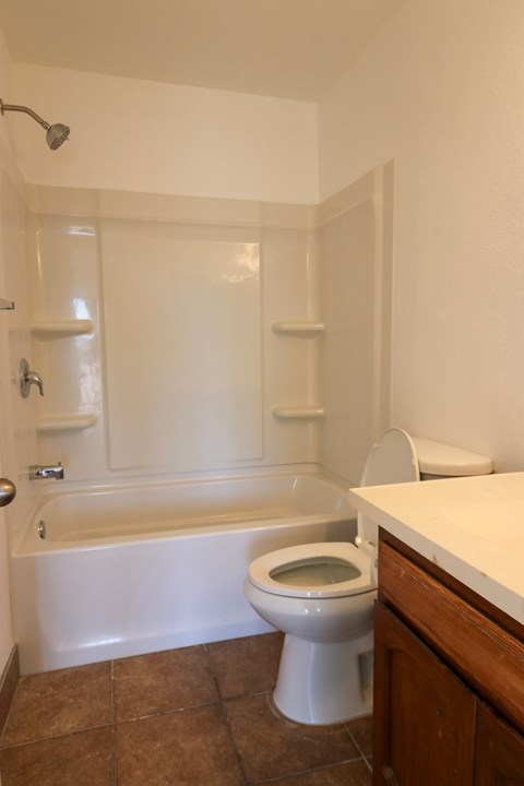 A white toilet in a bathroom with a white tub and shower.