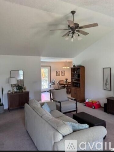 A living room with a couch, a chair, a side table, and a ceiling fan.