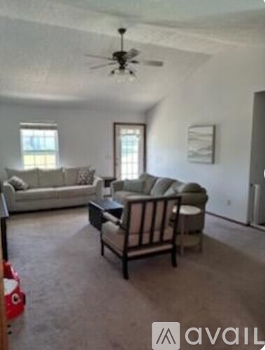 A living room with a couch, chair, and a fan.