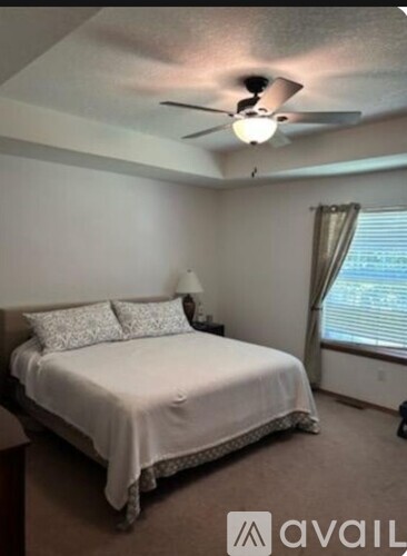 A bedroom with a bed, pillows, and a ceiling fan.