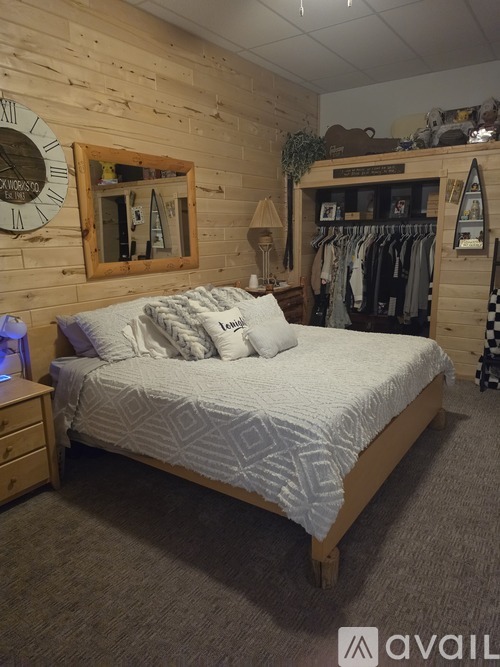A bedroom with a bed, nightstand, and a wall clock.