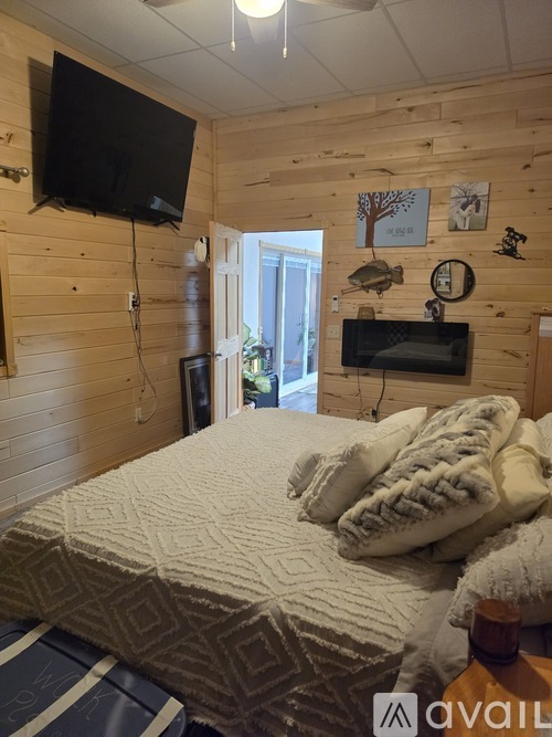 A bedroom with a bed covered in a white comforter and a wooden wall.